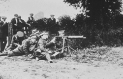 Local residents watching troops use an early machine gun