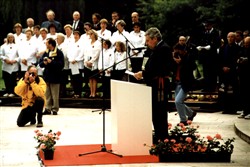 Colour photograph showing a man reading a speech possibly at a memorial