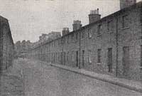 Black and white photograph of a street showing several houses on the right-hand side