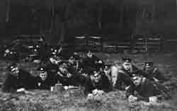 Black and white photograph showing several men in uniform laying down in a field.
