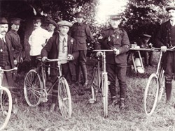Photograph of a soldier and three men with bicycles.