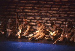 Slide of 7 soldiers sat or lying on the floor in front of a 'wall'