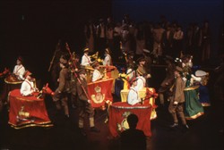 Slide of civilians stood on the stage with a parade of soldiers and cavalry in the foreground