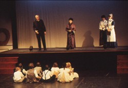 Slide of four adults on stage talking to children