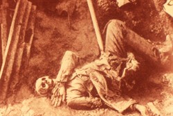 Slide of a photograph of a body in the bottom of a trench