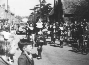 Girl pipers marching along a street.