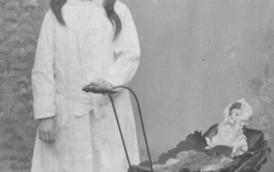 Postcard of girl with doll in pram.