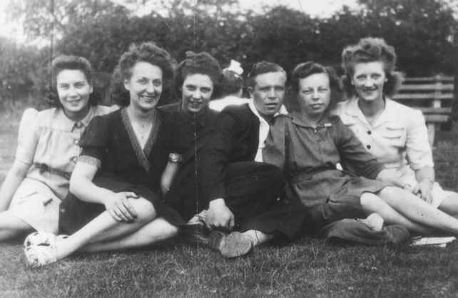 Group of six sitting on the grass incl. Audrey Willison.