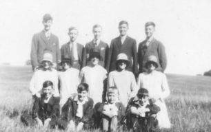 Group of five men, five women and four boys in a field.