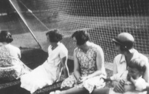 Ladies sitting against netting.