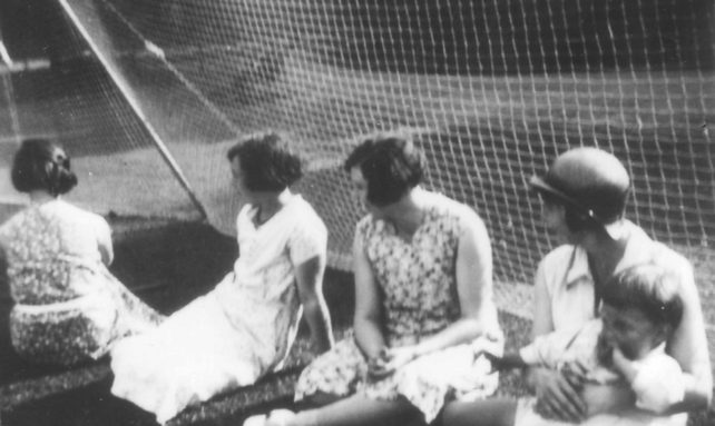Ladies sitting against netting.