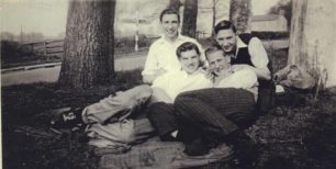 Four young men seated by a road