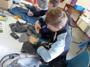 A boy cutting up an old pair of jeans