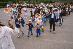 The goodbye parade sets off from the playground of Newlyn Pace First School. Teacher Julia Upton holds two children’s hands.