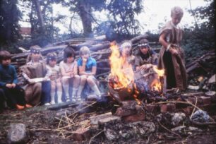 Young tribe members sitting around a camp fire