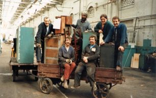 Six men moving their equipment on a trolley