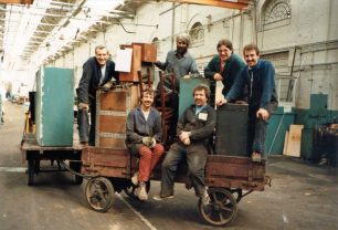 Six men moving their equipment on a trolley