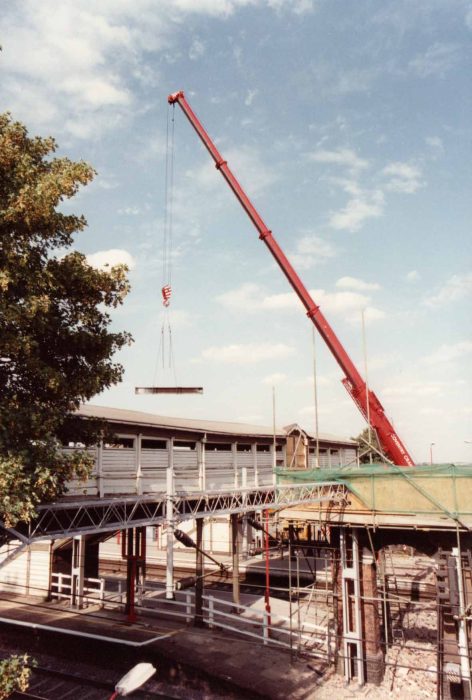 The crane lifting steel girders over the footbridge & into the car park