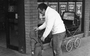 A man with a small child outside a Co-op shop