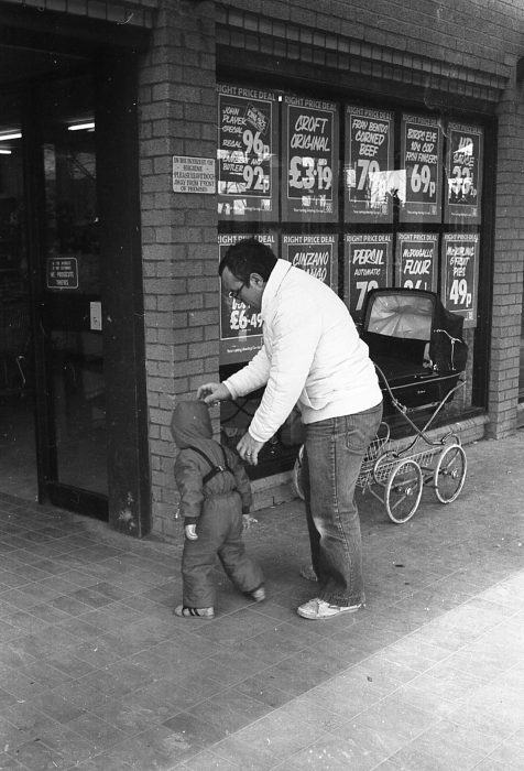 A man with a small child outside a Co-op shop