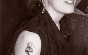 Woman with earrings and a snake-and-cross tattoo