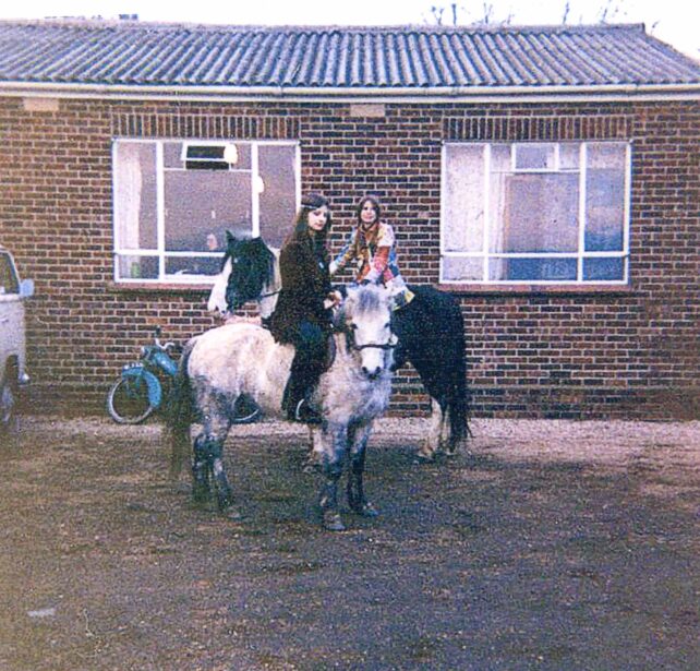 Two girls on horses outside youth centre building