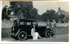 Photograph of a car and people.